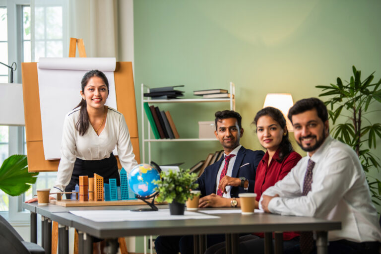 Confident Indian businesswoman presenting to a professional team in a modern office setting